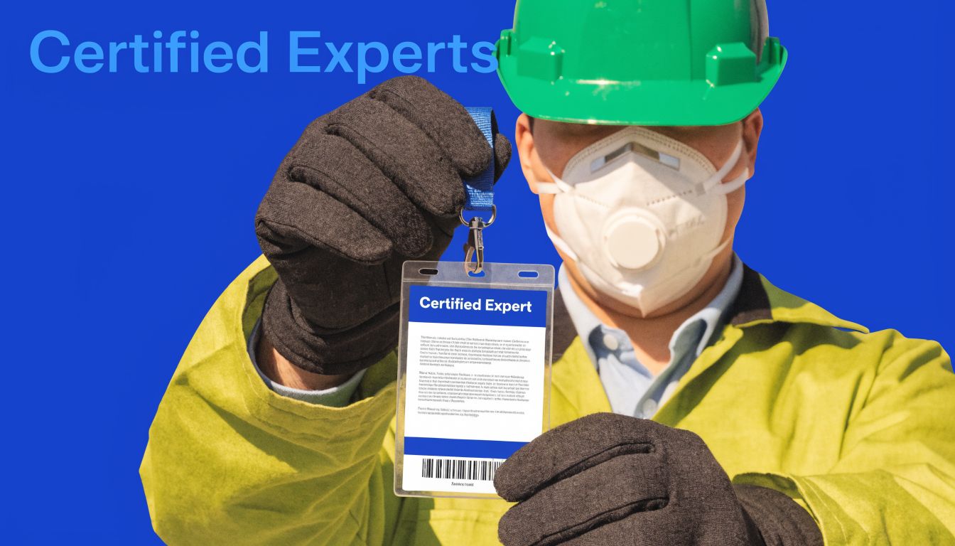 A mold remediation expert wearing a green hard hat, protective mask, and gloves holding a certified expert badge.