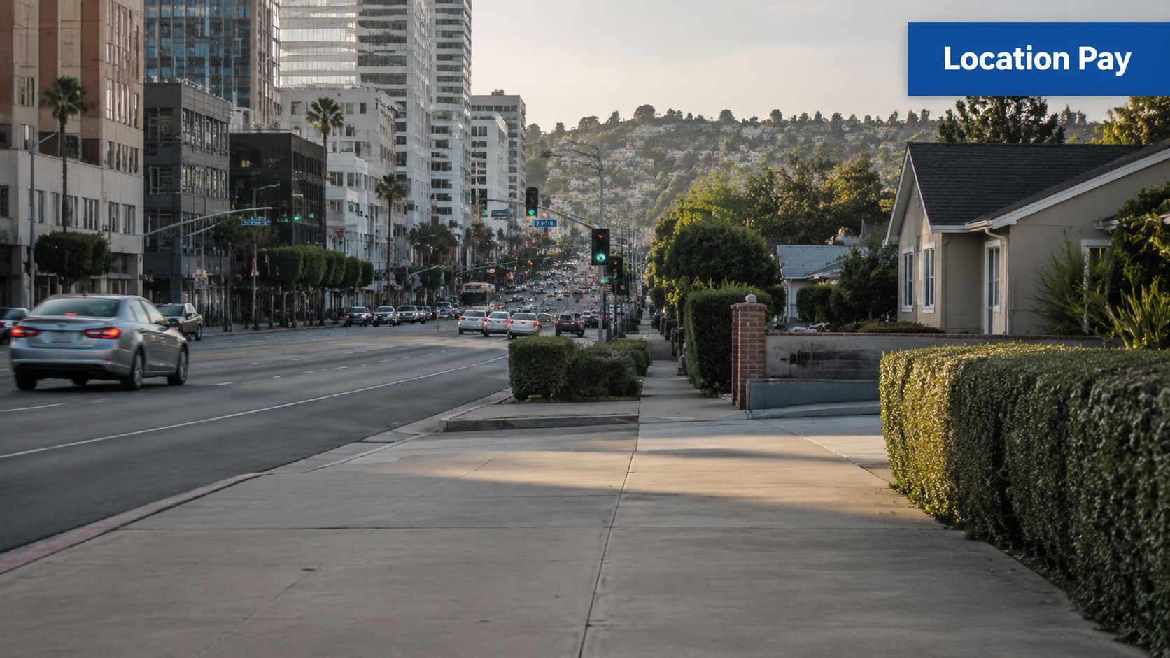 A scenic view of a sunny city street with traffic, modern buildings, and residential houses nearby.